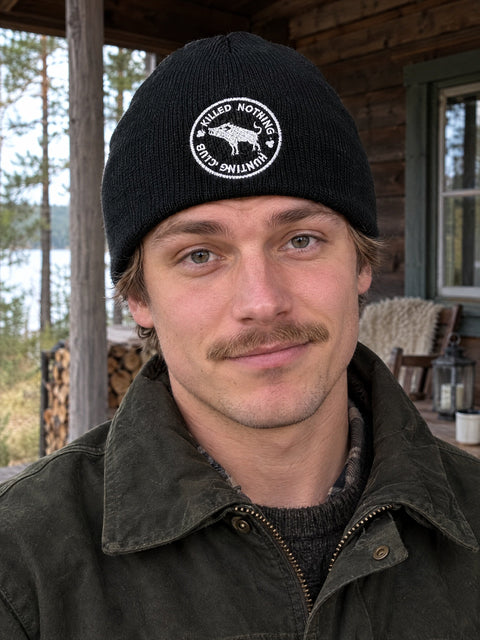 Killed Nothing Hunting Club på svart Hatitude Beanie, buren av en yngre vuxen.