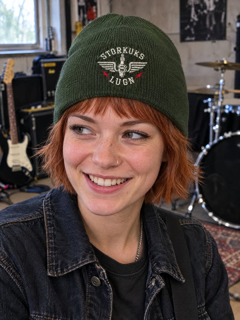 Storkuks Lugn på olivgrön Hatitude Beanie, buren av en yngre vuxen.